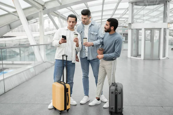 在现代机场室内 一组男性游客使用智能手机上的旅行应用程序与手提箱站在一起 旅游移动服务及应用广告 全长铅球 — 图库照片