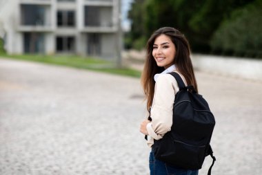 Sırt çantasıyla gezen güzel beyaz kız öğrencinin üniversitede, açık havada, kampüste boş alana bakmasına sevindim. Ad ve teklif, öğrenim, bilgi, eğitim