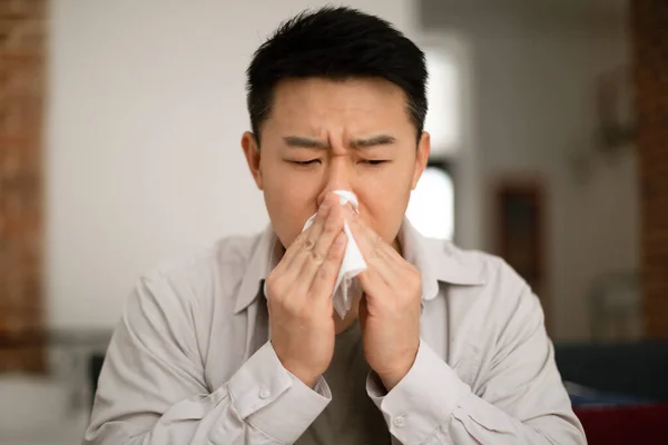 亚洲中年男人坐在家里打喷嚏 用餐巾纸 患感冒 流感或过敏 感到恶心 复制空间的画像 — 图库照片