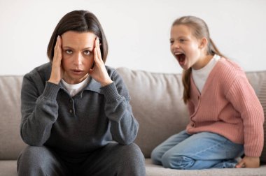Kızgın, agresif, Avrupalı genç bir kız oturma odasının içinde yorgun milenyum kadınlarına bağırıyor. Anne ve kız arasındaki ilişki sorunları, kavga, histeri.