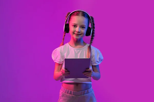 머리를 소녀가 디지탈 태블릿 헤드폰을 사용하여 웃으며 비디오 게임을 하거나 — 스톡 사진