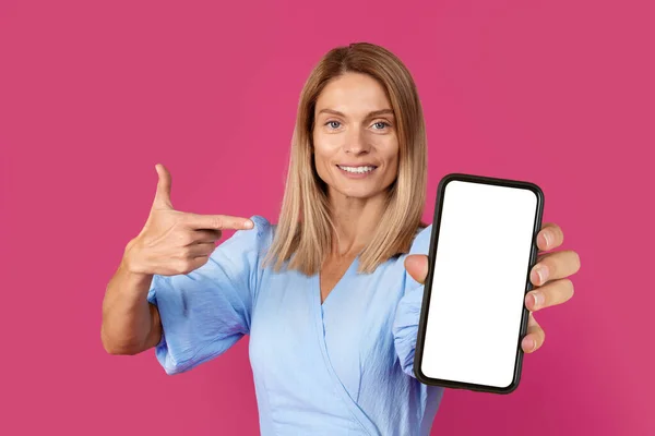 Cheerful Middle Aged European Blonde Lady Pointing Finger Smartphone Blank — Stock Photo, Image