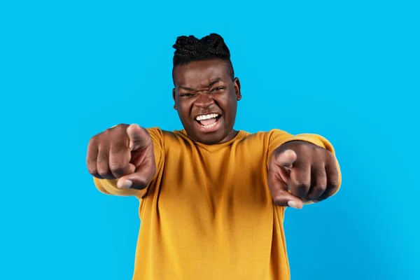 Portrait Of Excited Black Guy Pointing At Camera With Two Hands, Emotional Black Man Indicating Somebody, Shouting Gotcha While Standing Isolated Over Blue Studio Background, Copy Space