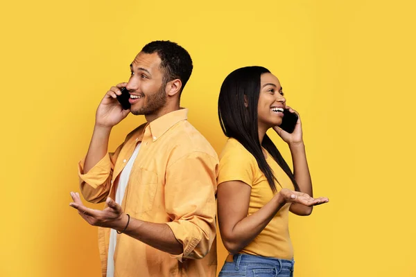 何千年ものアフリカ系アメリカ人のボーイフレンドと女性がスマートフォンで呼び出し 黄色のスタジオの背景に隔離された話 ゴシップコミュニケーションのための装置良い知らせロマンチックな — ストック写真