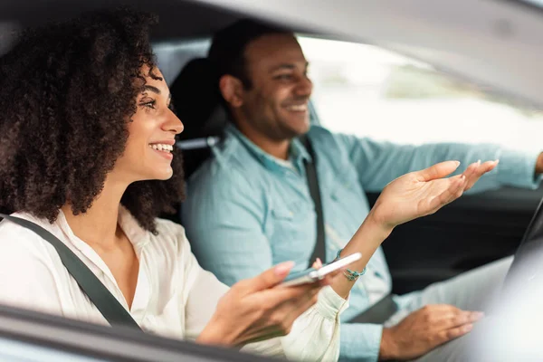ナビゲーションに携帯電話を使用したアラビア語の配偶者の笑顔新しい車の運転 スマートフォンでのアプリケーションの使用方法を示す妻高級車の中に座っている サイドビュー 選択フォーカス — ストック写真