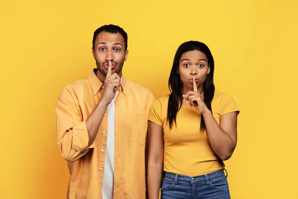 アフリカ系アメリカ人の何千人もの男性と女性が口に指を入れて 黄色のスタジオの背景にシェーのサインを隔離しました 広告やオファー — ストック写真