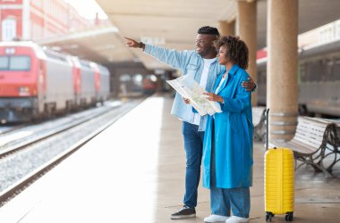 Şuradan. Siyah Gezginler, tren vardıktan sonra tren istasyonunda beklerken şehir haritasını kontrol ediyorlar. Genç Afrikalı Amerikalı erkek ve kadın nereye gideceklerini planlıyorlar.