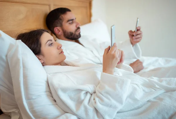 Bir Çift Cep Telefonu Kullanıyor Mesajlaşıyorlar Yatakta Uzanıyorlar Beyaz Bornozlarını — Stok fotoğraf