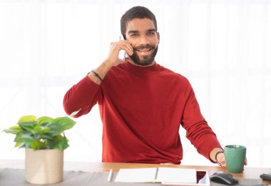 Neşeli, pozitif gülümseyen çekici bir genç adamın portresi günlük kıyafet yöneticisi ya da girişimci masada oturuyor, kahve içiyor, telefon görüşmesi yapıyor, ofiste çalışıyor, uzay kopyaları yapıyor.