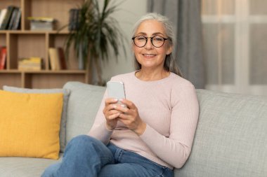 Gözlüklü, telefonda yazan, mesajlaşan, sohbet eden, oturma odasında boş vakitlerinde internette sörf yapan beyaz bir kadın olmasına sevindim. Sosyal medya uygulaması, reklam ve teklif, teknoloji ile yaşam tarzı