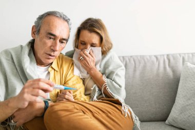 Kıdemli bir adamın karısının ateşini ölçmesi peçeteye hapşıran kadın, evde hasta kadınla ilgilenen sevgili koca, fotokopi odası. Mevsimsel hastalık konsepti
