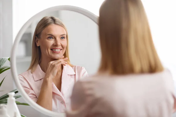 Концепция Skincare Привлекательная Женщина Средних Лет Смотрящая Зеркало Ванной Комнате — стоковое фото