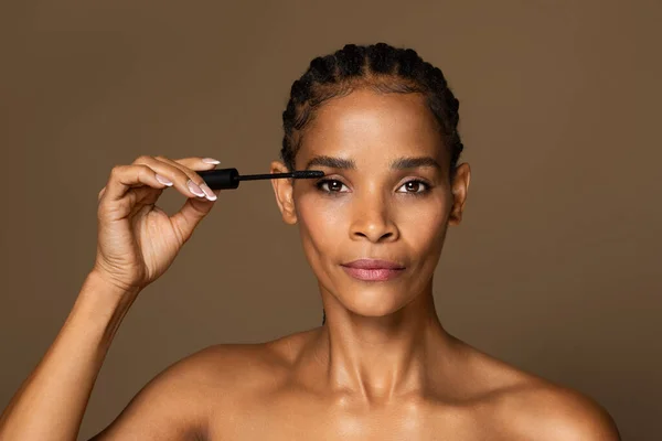 ブラウンの背景に孤立したブラシでまつ毛にマスカラを適用する美しいアフリカ系アメリカ人の中年女性 美容ケア ルーチン手順 化粧品 ブログのレッスン — ストック写真