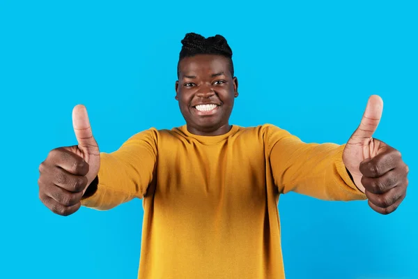 不错的选择 快乐兴奋的黑人男子在摄像机前举起两个拇指 积极的非洲裔美国青年男子站在蓝色的背景上举手投足表示赞同 复制空间 — 图库照片
