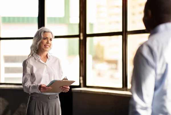 stock image Successful Job Interview. Cheerful Female Employer Meeting With New Male Employee Standing Holding Folder With Papers In Modern Office. HR Manager Career Concept. Selective Focus On Businesswoman