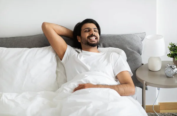 Beyaz Tişörtlü Mutlu Genç Yakışıklı Orta Doğulu Erkek Yatakta Uzanıyor — Stok fotoğraf