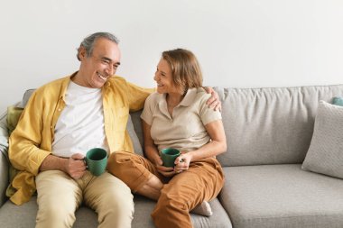 Mutlu eşler kahve içip konuşuyorlar, birlikte vakit geçiriyorlar, evdeki kanepede oturuyorlar, boş yer var. İlişki ve iletişim kavramı