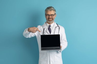 Gülümseyen, gri saçlı, olgun, beyaz saçlı, bilgisayarını siyah ekranlı gösteren bir doktor. Hoş bir tele-sağlık sitesi, mavi stüdyo geçmişi, maket, kopyalama alanı öneriyor.
