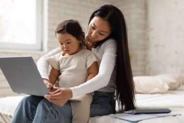 Bebekle çalış. Koreli anne evde cep telefonuyla konuşmakla meşgul. Bebek kızını ve dizüstü bilgisayarını tutuyor. Serbest Çalışan Anne aynı anda birden fazla iş yapıyor. Serbest Kariyer ve Annelik