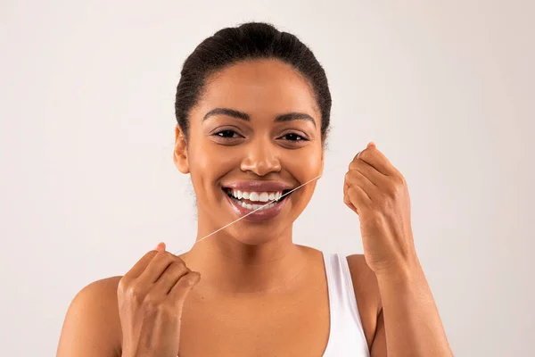 幸せなアフリカ系アメリカ人の歯の女性モデルの肖像きれいな口腔衛生のために口を流れる 歯のフロスで歯を洗浄する黒の女性スタジオの背景に隔離されたクローズアップ — ストック写真