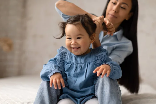 Loving Asian Mommy Making Ponytails Doing Baby Daughters Hair Sitting — Stock Photo, Image