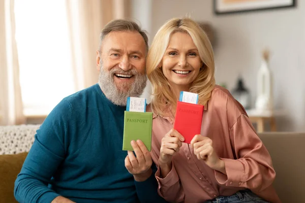 Ucuz Biletler Pasaportlarını Gösteren Evdeki Koltukta Oturan Kameraya Gülümseyen Olgun — Stok fotoğraf