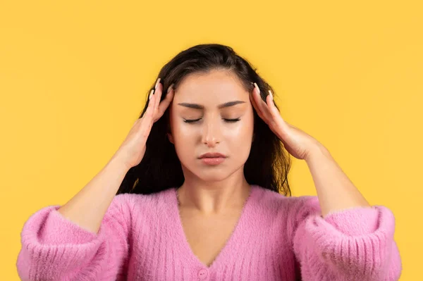 黄色のスタジオの背景に隔離された頭痛に苦しんで閉じ目を持つ悲しい千年紀のアラブの女性を疲れ クローズアップ ストレス 片頭痛 医療問題 — ストック写真