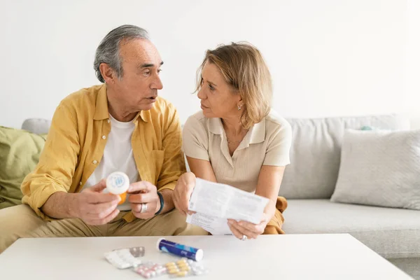 Senior Spouses Reading Leaflet Drugs Drinking Pills Sitting Sofa Living — Stock Photo, Image