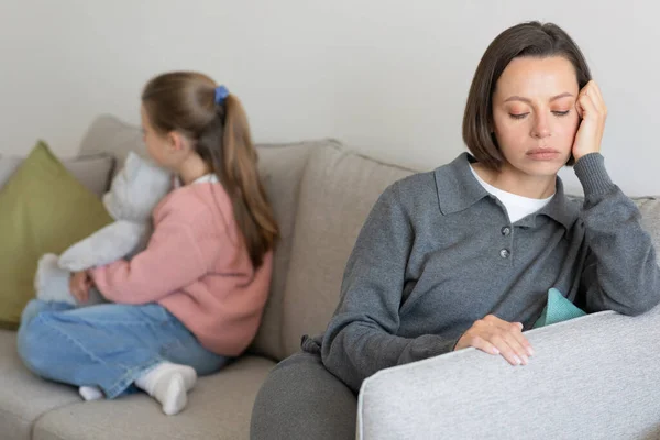 Angry sad offended european millennial mother ignores teenage girl hug toy in living room interior after quarrel. Stress, scandal, difficult at family, problems at relationships at home