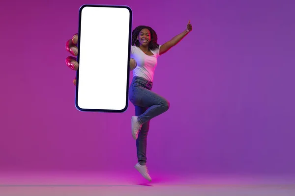 Radosny Młody Czarny Kobieta Jumping Big Blank Smartphone Neon Light — Zdjęcie stockowe