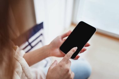 Milenyum Avrupalı kadın telefonda boş ekranla yazıyor, minimalist oturma odasında dinleniyor, omuz hizasında, kırpılmış, kapatılmış. Sosyal medya sohbeti, blog uygulaması, evde çalışma