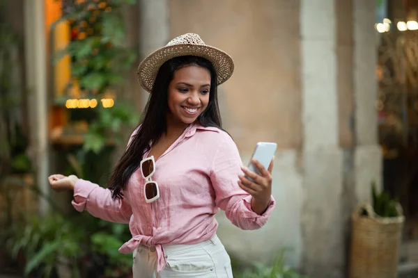 Zadowolona Młoda Milenijna Czarna Turystka Korzystająca Telefonu Rozmawiająca Sieciach Społecznościowych — Zdjęcie stockowe