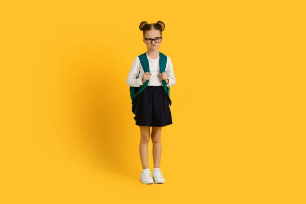 Porträtt Grumpy Little Schoolgirl Med Ryggsäck Stående Över Gul Studio — Stockfoto