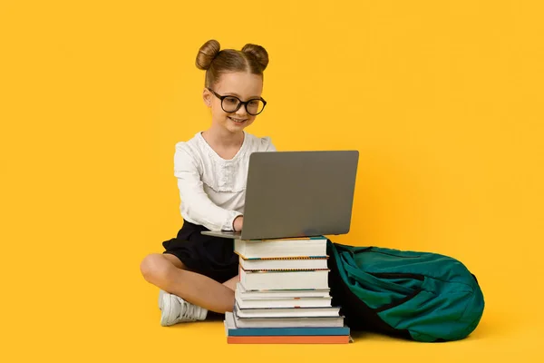 Cute Little Schoolgirl Robi Prace Domowe Laptopie Nad Żółtym Tle — Zdjęcie stockowe