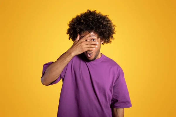 悲しいショックを受けた大人のアフリカ系アメリカ人の巻き毛の男紫のTシャツは黄色のスタジオの背景に手で顔をカバー ストレス 恐怖感情や表情 オファー — ストック写真