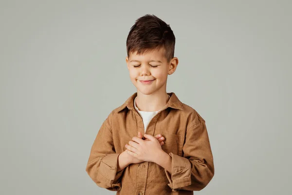 Altı Yaşında Elleri Göğsünde Dua Eden Gri Arka Planda Izole — Stok fotoğraf
