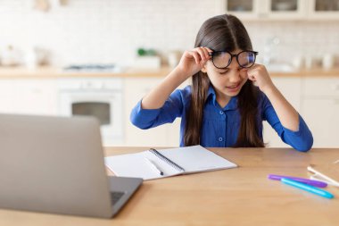 Göz yorgunluğu sorunu. Diz üstü bilgisayarda ödev yapan liseli kız yorgun ve evde oturan gözlüklü kız yorgunluğu ve kuru göz sendromu yüzünden acı çekiyor. Çocuk Görme Sorunları