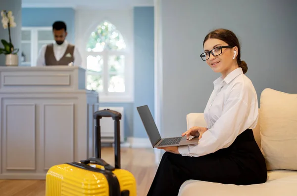 Businesswoman Using Laptop Wearing Wireless Earphones Smiling Camera Sitting Hotel — Stock Photo, Image