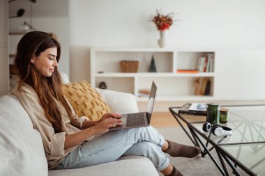 Uzaktan çalışma, online ders ve alet. Minimalist oturma odasının içinde, profilini bilgisayarda yazan Avrupalı kadına sevindim. Serbest meslek, iş ve iş evde