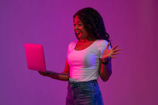 Cool Website. Portrait Of Excited Black Woman With Laptop In Hands Under Neon Lighting, Overjoyed African American Lady Celebrating Success With Laptop, Standing Over Purple Studio Background