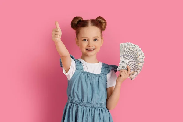 Cute Little Girl Holding Money Cash Showing Thumb Camera Smiling — стокове фото