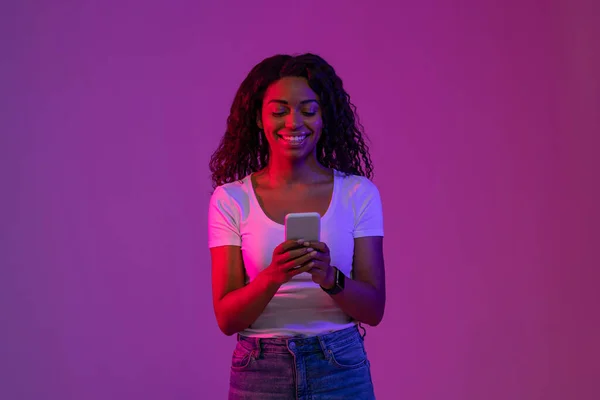 Boldog Fiatal Fekete Használ Okostelefon Miközben Áll Fényes Neon Fény — Stock Fotó