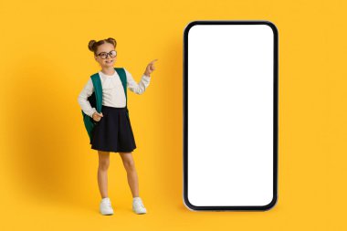 Şuna bak. Beyaz ekranlı, boş akıllı telefonu işaret eden, sırt çantalı, Mobil Uygulama ya da Web Sitesi Tasarımı İçin Yer Gösteren, Sırt çantalı kız çocuğu gülümseyen sevimli liseli kız.