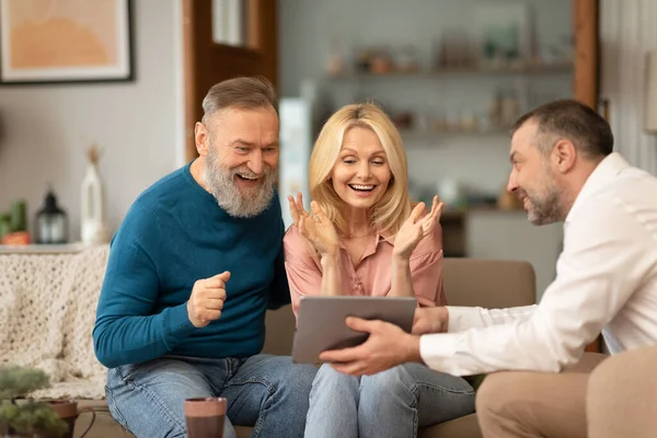 Man Showing Digital Tablet Computer Excited Mature Buyers Pareja Celebrando — Foto de Stock