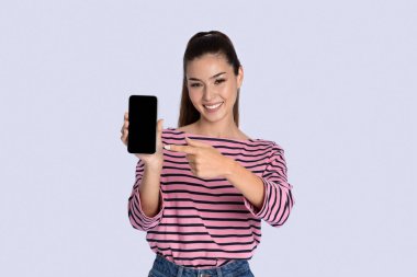 Oldukça neşeli esmer, uzun saçlı, gündelik kıyafetler giyen, elinde siyah ekranlı akıllı telefon tutan, güzel bir online teklif sunan, gri stüdyo geçmişi olan, model, kopya alanı olan bir kadın.