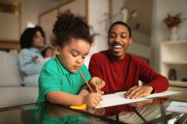 Mutlu ırklar arası aile evde vakit geçiriyor. Neşeli afro-amerikan babası küçük çocuğuyla boyama yaparken İspanyol kadın bebek bebekle kanepede oturuyor, geçmişi bulanık.