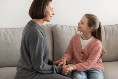 Olumlu Avrupalı bin yıllık anne el ele tutuşuyor, genç kızla konuşuyor, oturma odasındaki iletişimin tadını çıkarıyor. Aşk, destek, ilgi ve tavsiye, evdeki ilişkiler