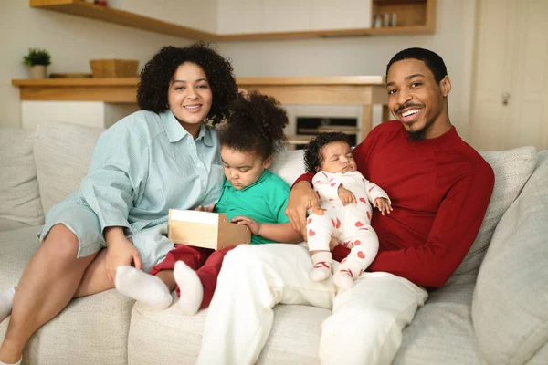 幸せな陽気な若い異人種間の家族の肖像黒夫とヒスパニック系の妻2人の愛らしい小さな子供とソファに座って 自宅で一緒に時間を楽しみ スペースをコピー — ストック写真