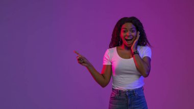 Şuraya bak. Fotokopi uzayını işaret eden siyahi kadın, Mor Arkaplan 'ın üzerinde neon ışığının altında dururken, Afro-Amerikan Mutlu Kadın Reklam için Boş Yer Gösteriyor, Panorama