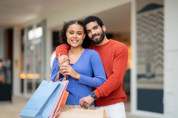 季节性销售 中东情侣抱着购物袋和色彩斑斓的纸包装站在外面拍照 家庭折扣优惠概念 — 图库照片